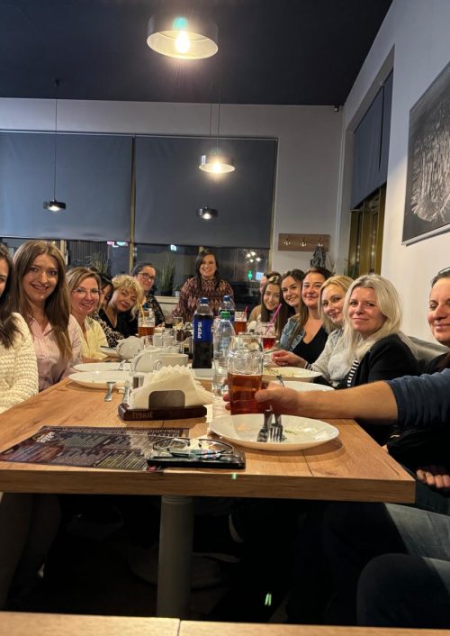 Zdjęcie grupowe kilkunastu osób siedzących przy długim, drewnianym stole w pizzeri w Pabianicach.